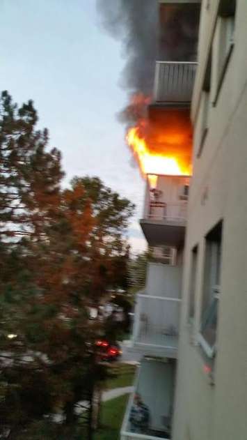 A resident photo of flames shooting from a fifth floor balcony at an apartment buildling on Rivard Ave., October 7, 2015. (Photo courtesy of Jackie Oke)