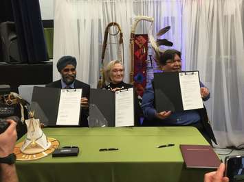 From left to right:  Harjit Sajjan, Carolyn Bennett and Tom Bressette sign the agreement for the return of the former Camp Ipperwash April 14, 2016 (BlackburnNews.com photo by Briana Carnegie)