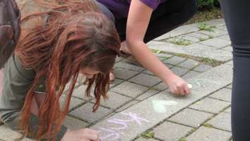 Students write supportive messages in chalk on sidewalk of Museum Square, June 7, 2016. (Photo by Miranda Chant, Blackburn, News)