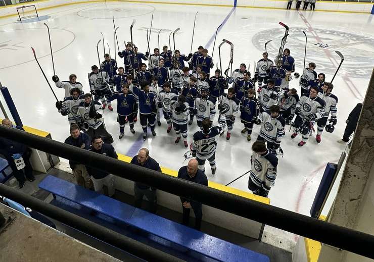 The Wheatley Omstead Sharks and Amherstburg Admirals raise their sticks in tribute to Sylvain Lessard during their game at Wheatley Arena, October 25, 2023. A jersey bearing the #11, which Lessard wore in Wheatley, is visible hanging from the railing in the lower left hand corner. Another jersey is visible at centre ice. Photo courtesy Wheatley Omstead Sharks/Facebook.