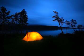 A tent lit up at dusk. © Can Stock Photo / mikdam